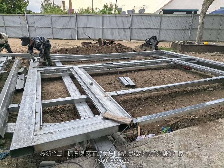 工人在户外场地焊接大型金属标牌骨架