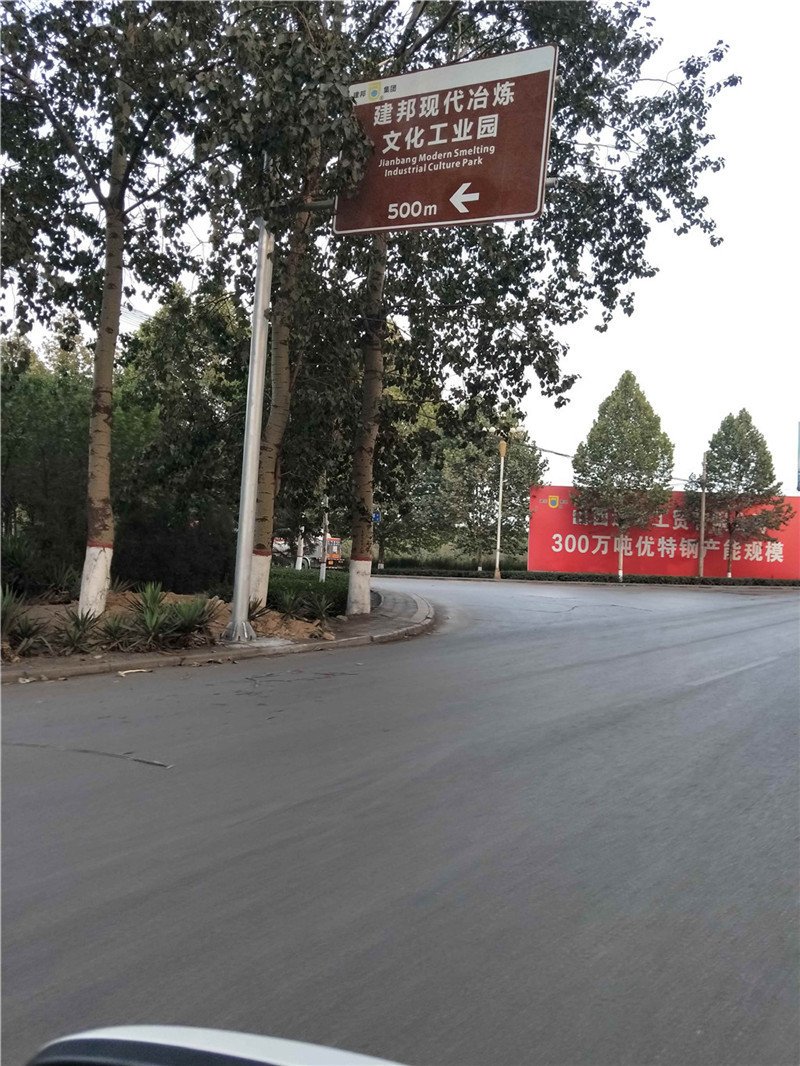 工业园区主干道棕色立柱式指路牌实拍：白色文字与左向箭头、距离提示