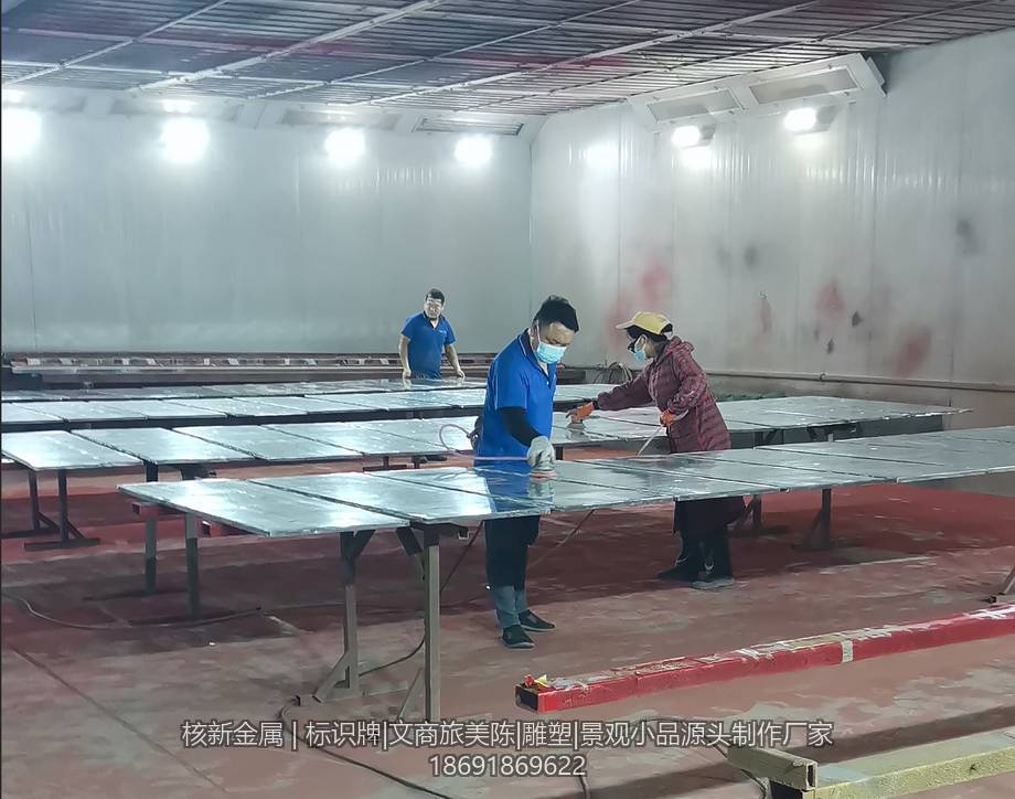 烤漆房内工人对平铺的金属面板进行喷涂作业
